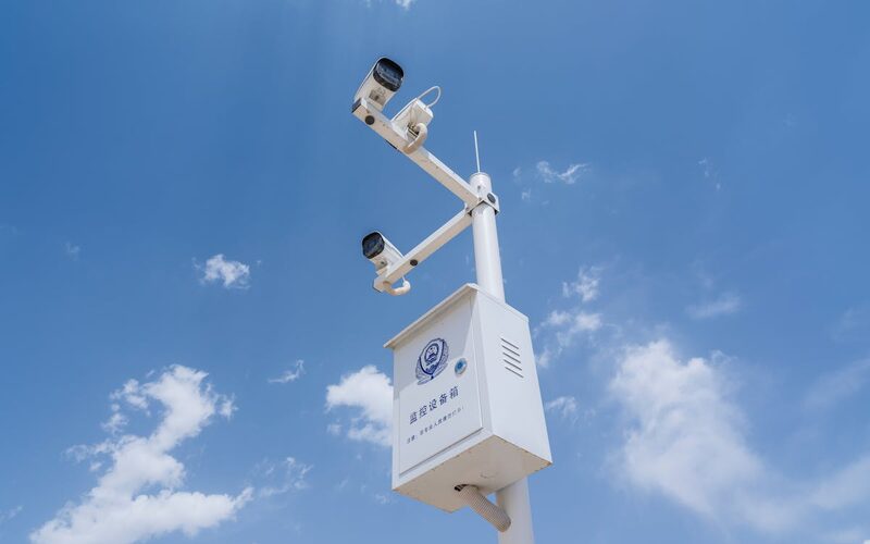 Megfigyelőkamera oszlopon, városi háttérrel